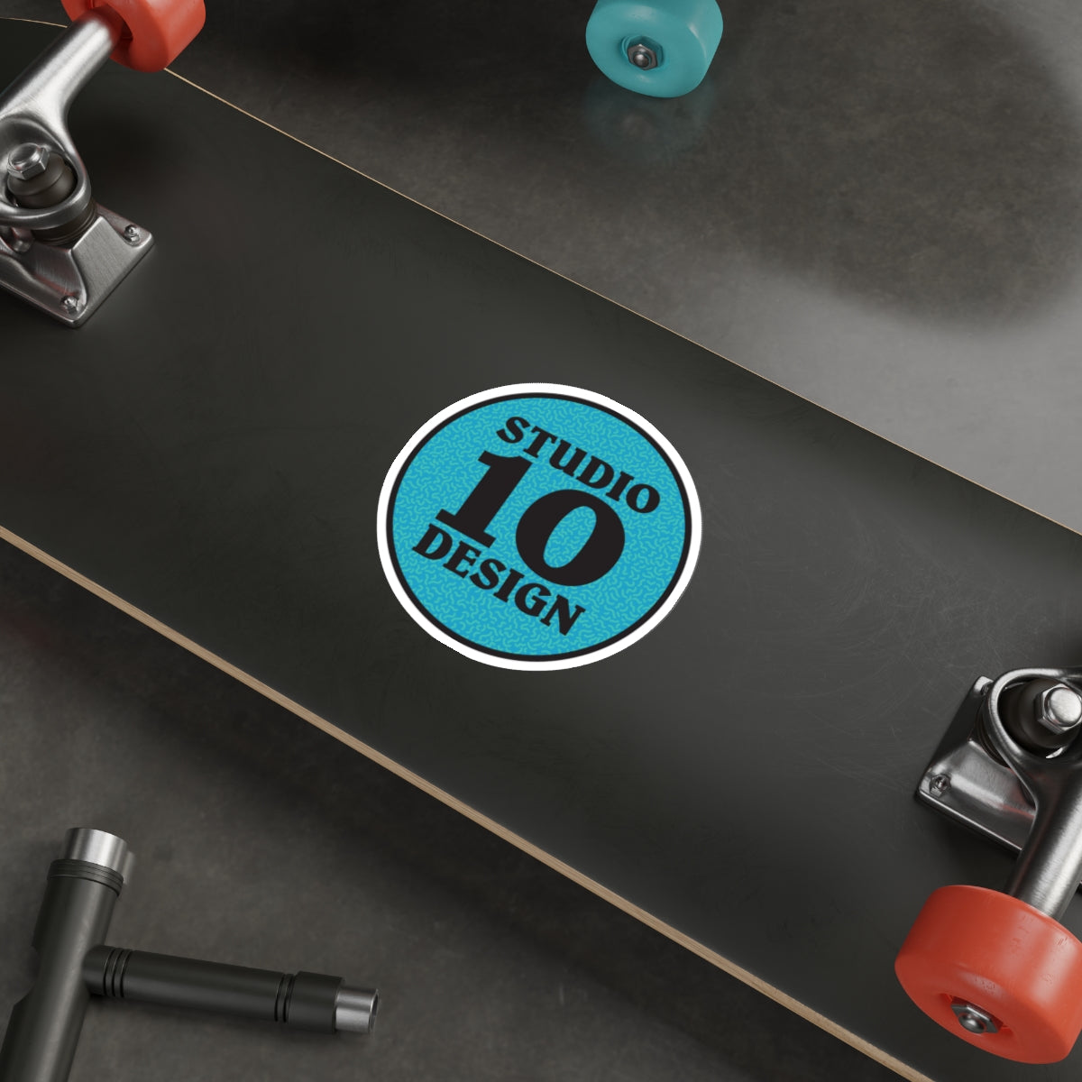 Four inch round vinyl sticker shown adhered to a skateboard deck